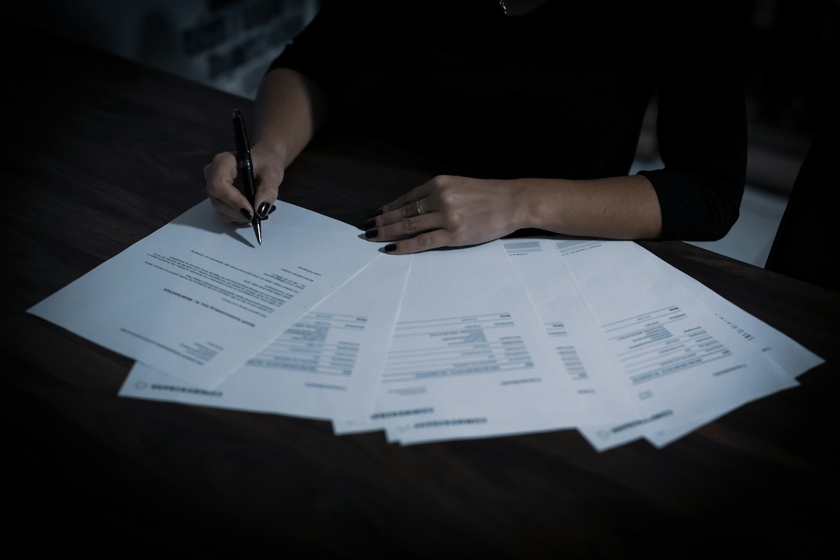 Osoba podpisująca komplet dokumentów formalnych rozłożonych na biurku